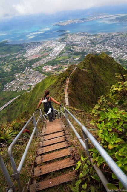 A tourist walks down a steep flight of stairs on a mountain.