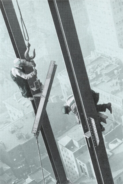 Two construction workers working on steel poles.