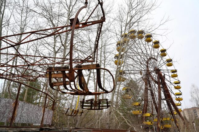 Rusty rides surrounded by overgrown vegetation at Pripyat Amusement Park