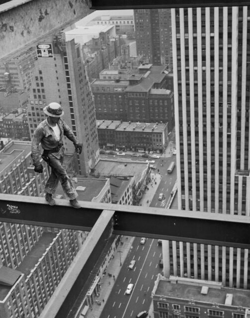 A construction worker walks steel girders high in the sky.