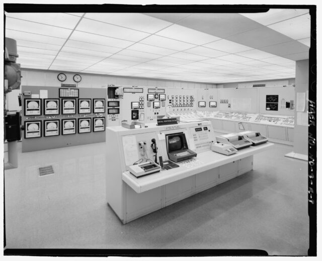 Inside a control room with computers and machines from the 1970s.