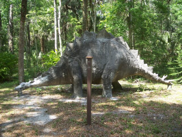 Large dinosaur statue in the middle of a wooded area at Bongoland
