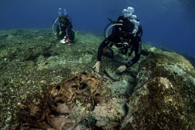 Two divers study a shipwreck.
