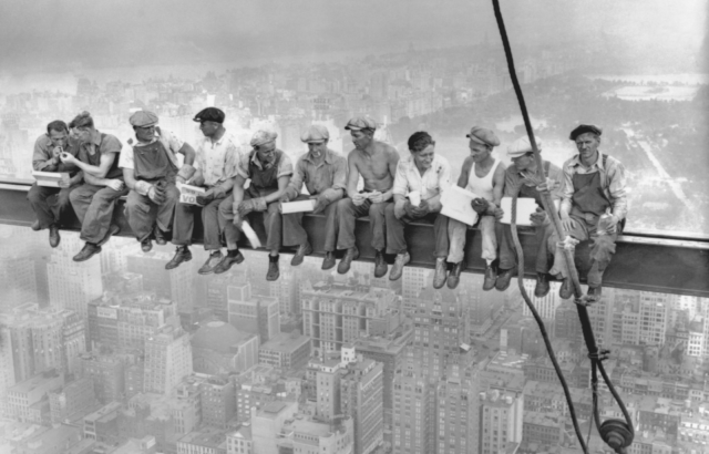 A row of men eating lunch on a steel girder.
