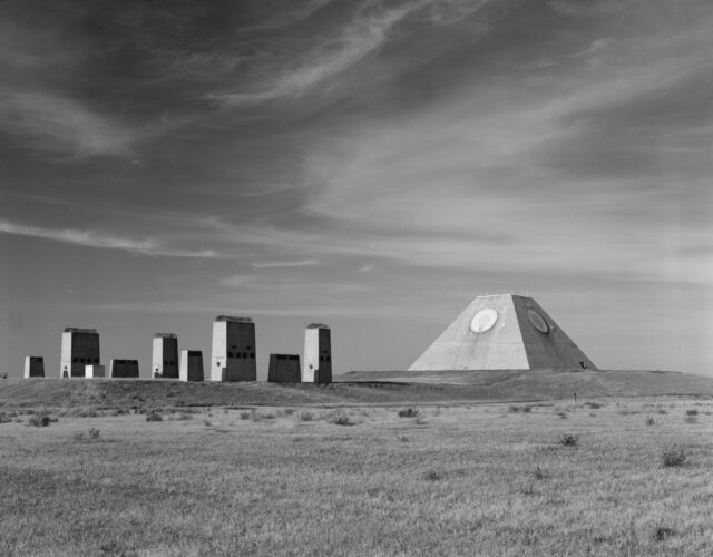 The Pyramid of North Dakota in a field with other structures near it.