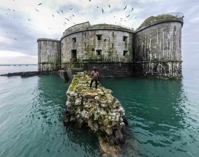 A person walking on the stones of Stack Rock Fort.