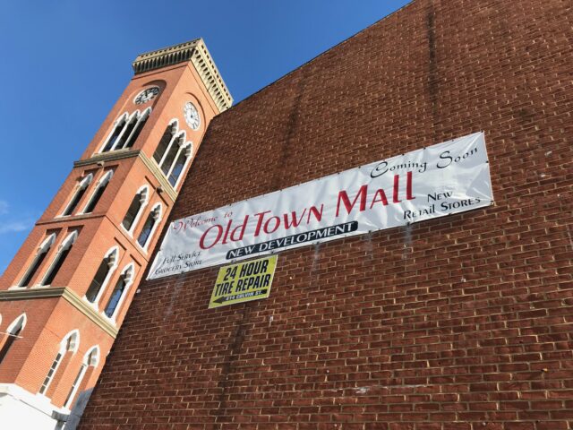 A brick wall with a banner on the side, a tower in the background.