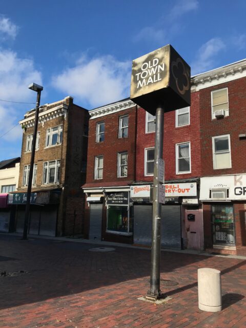 Abandoned buildings, a sign on a sidewalk reading "OLD TOWN MALL"