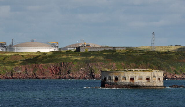 Stack Rock For on water, land in the background.